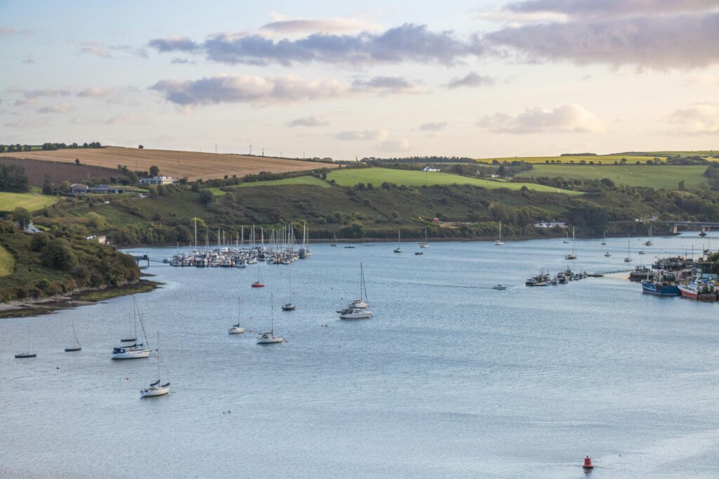Tranquil view of boats anchored in Kinsale Harbor, Ireland, under a cloudy sky.